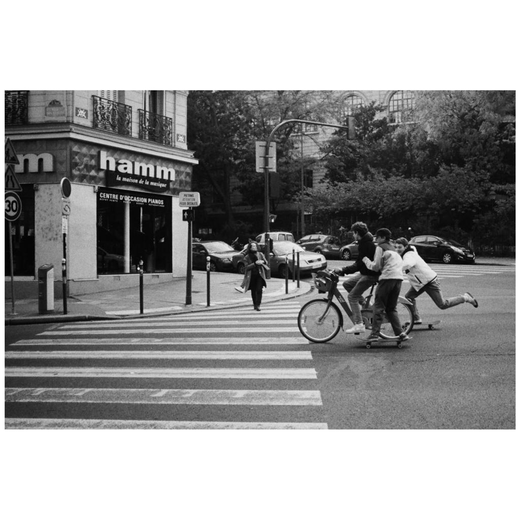 street photography Paris trois jeunes en skate et vélo